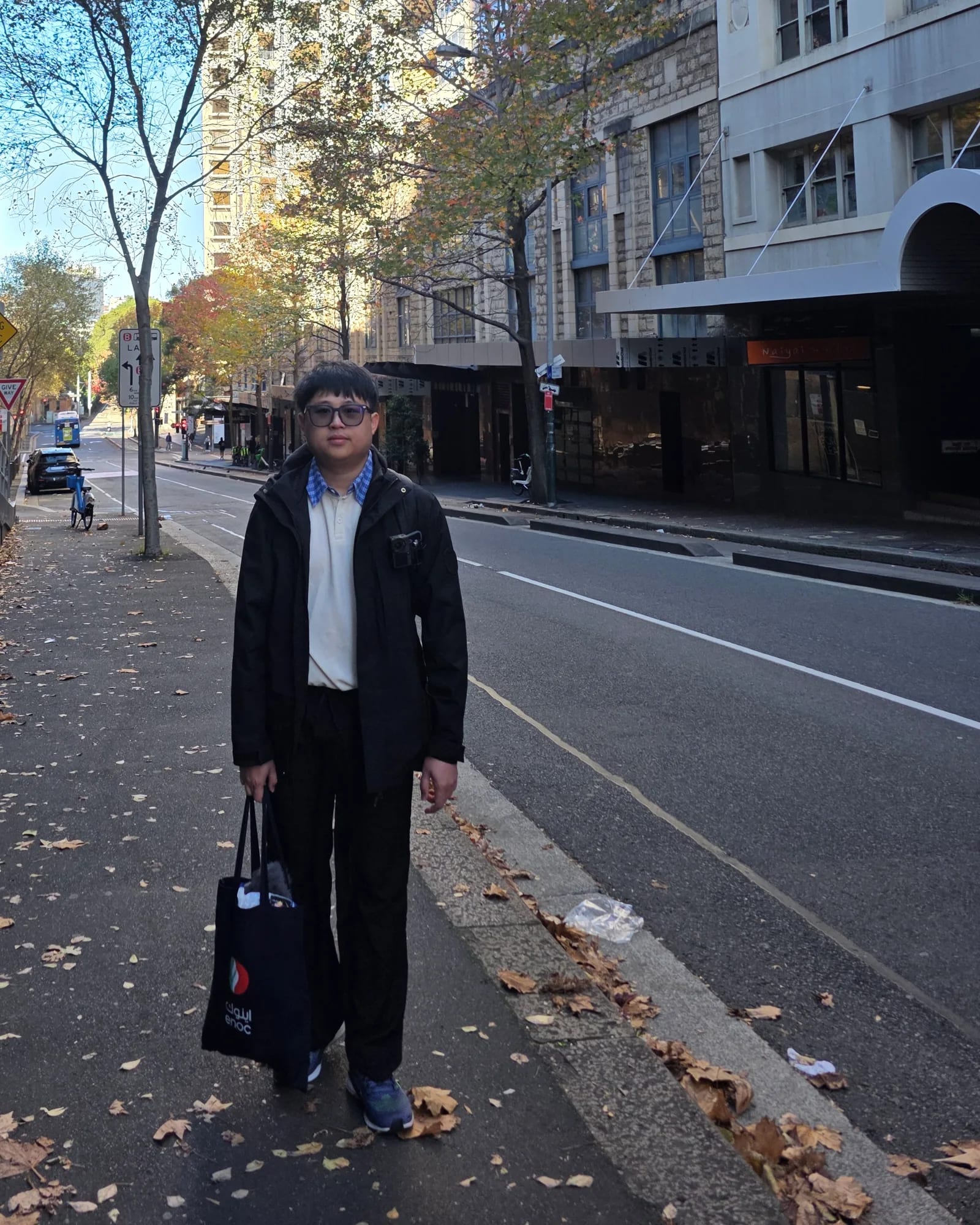 Yun Wah Lee standing on a city street lined with tall buildings